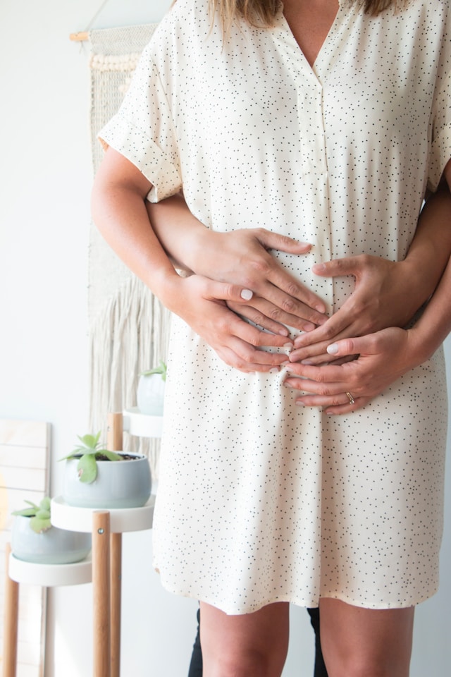 femme enceinte avec les mains de son partenaire sur son ventre rond