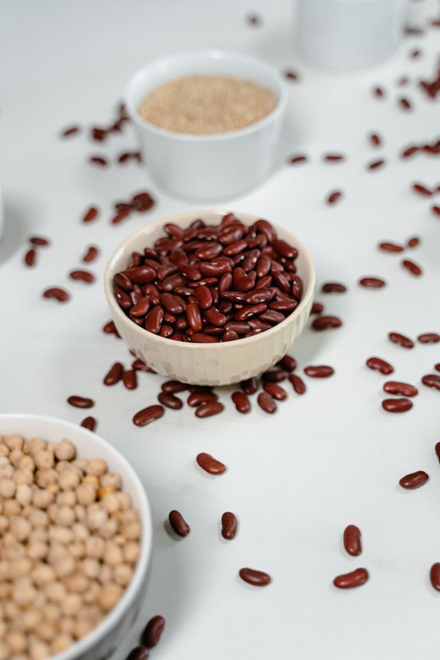 Haricots rouges et pois chiches dans des ramequins blancs sur une table blanche 